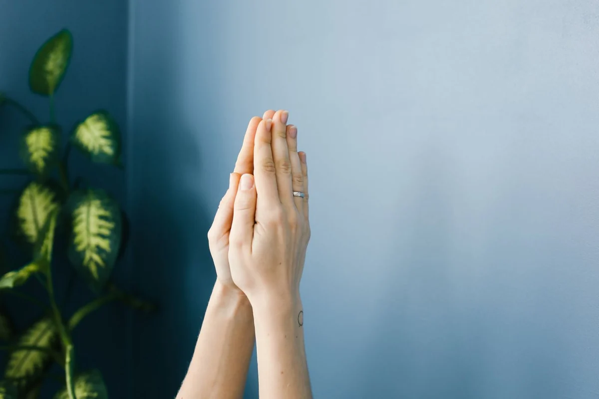 Hands and delicate jewelry against a tranquil blue backdrop