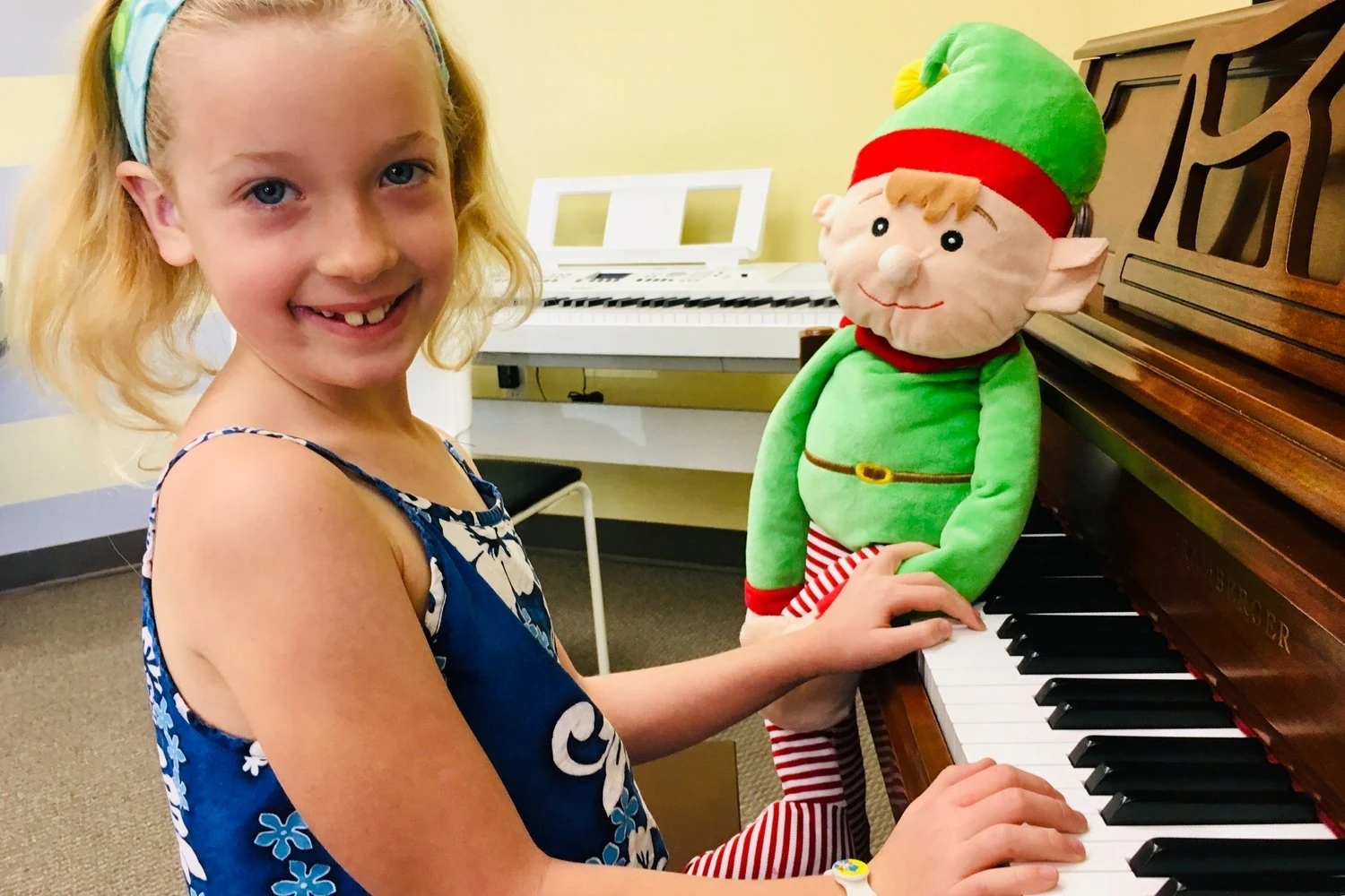 A student beside a piano and a classroom toy.