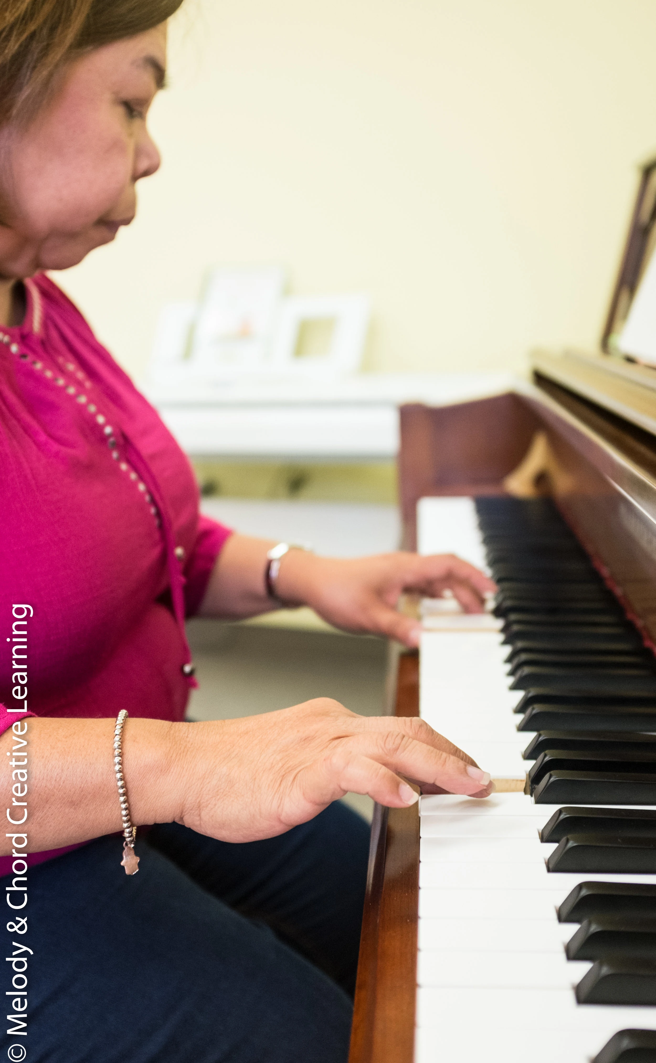 A learner playing an upright piano.