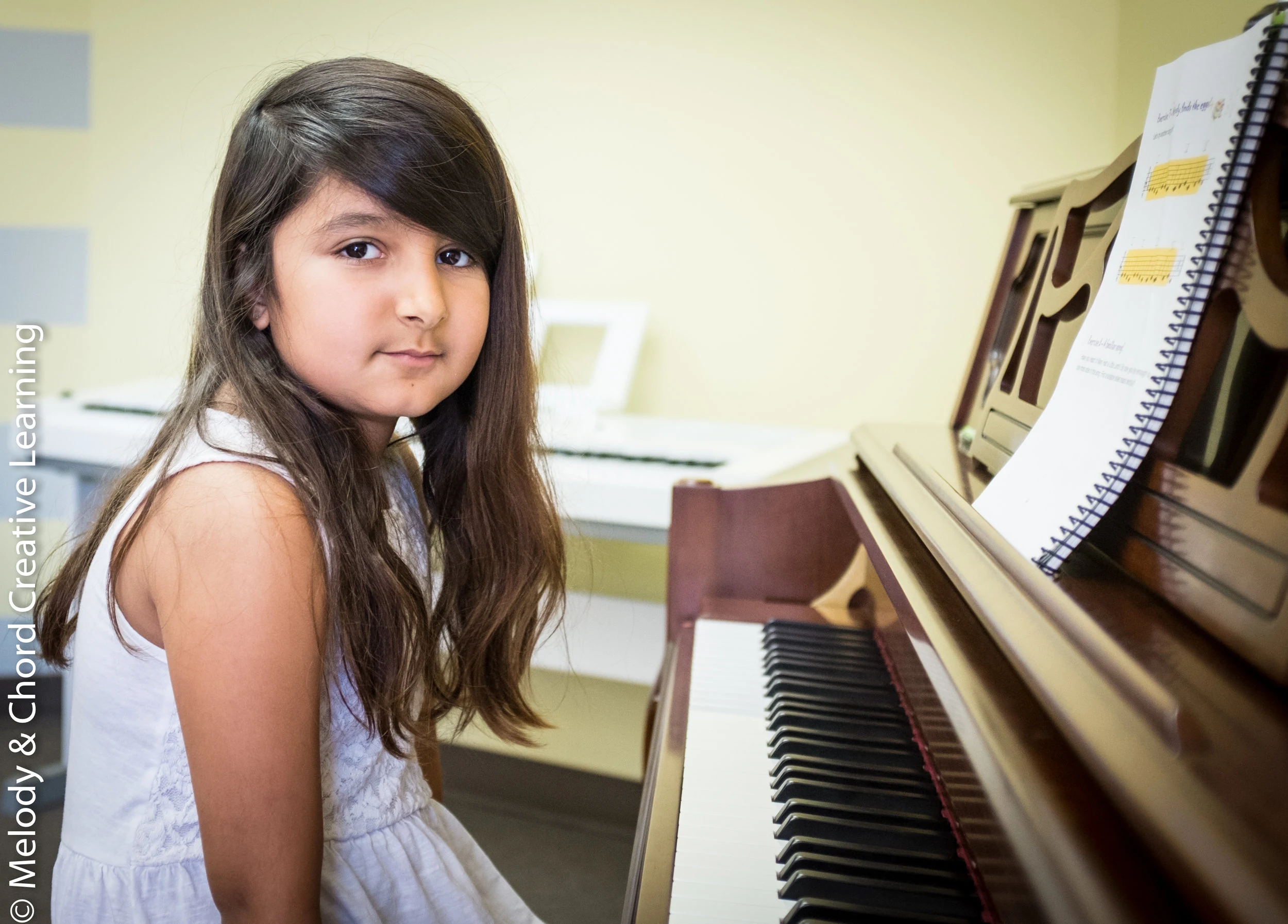 A student seated beside a piano.