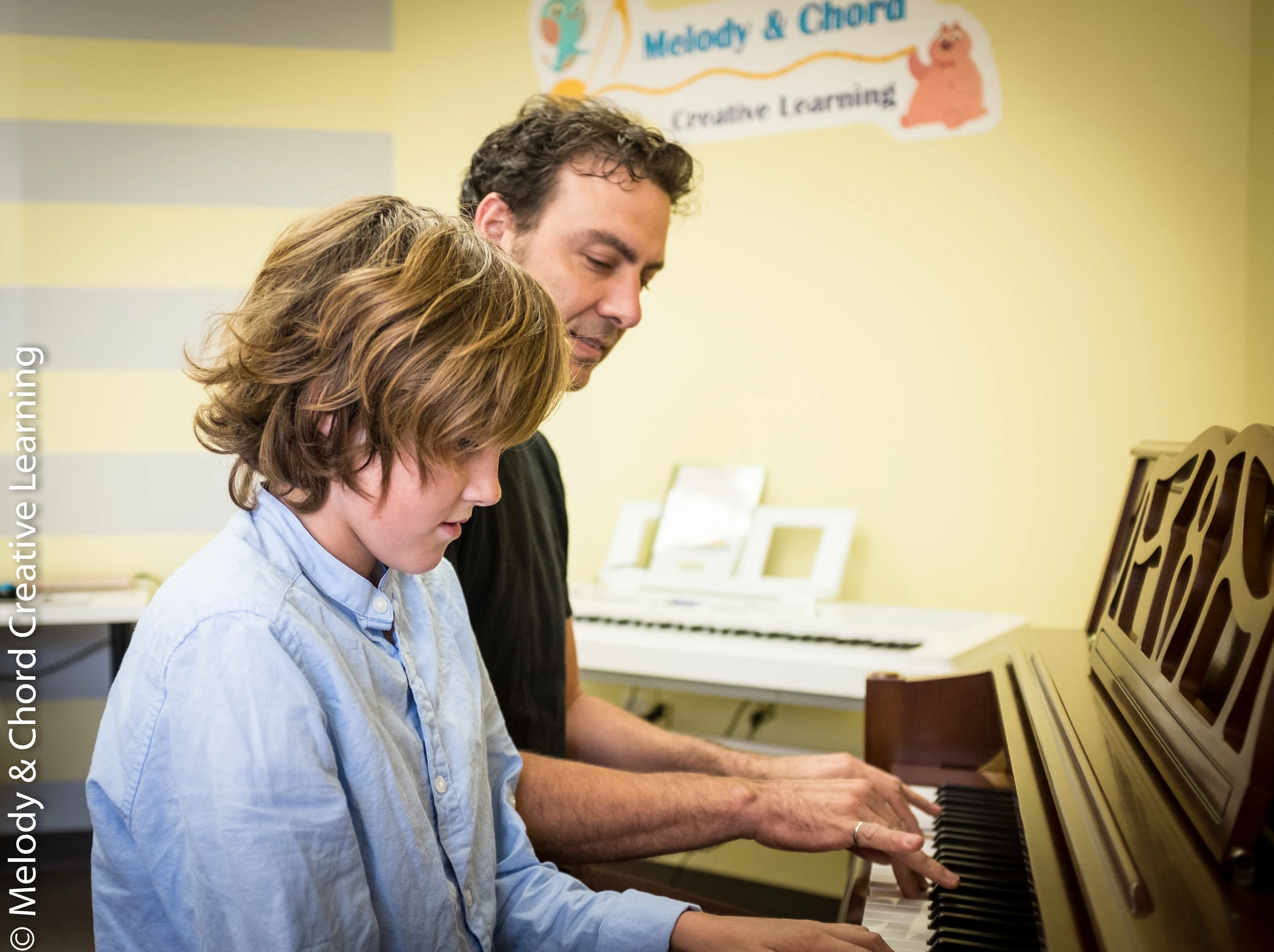 Music coaching at an upright piano.