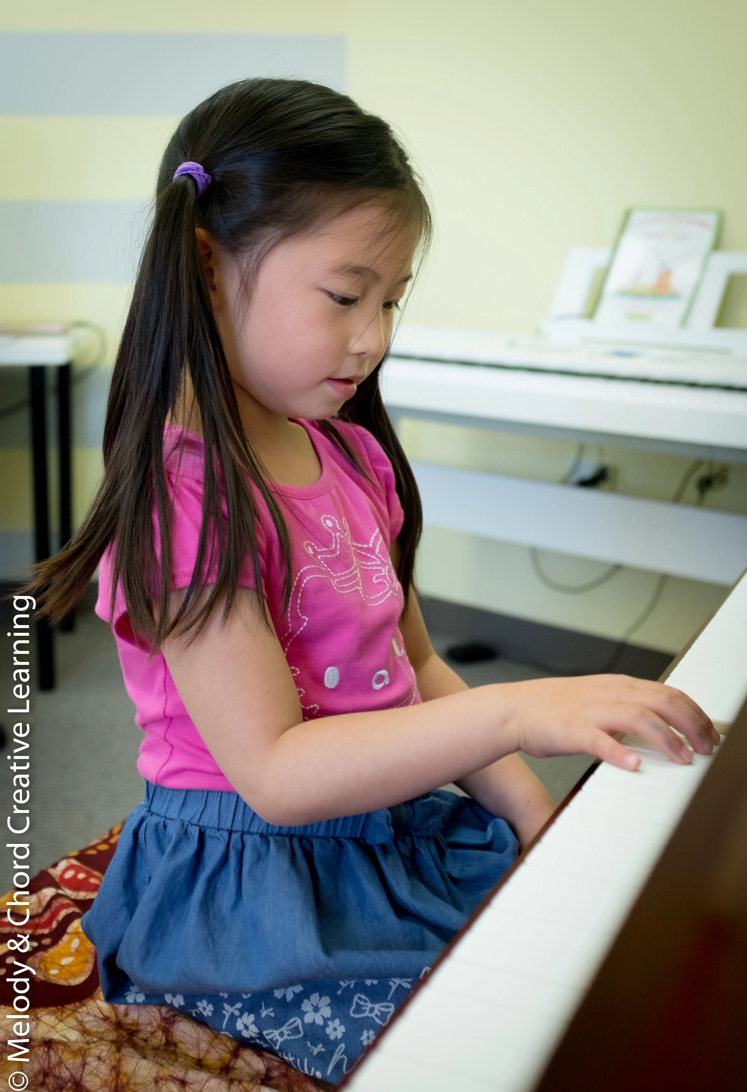 A student playing an upright piano.
