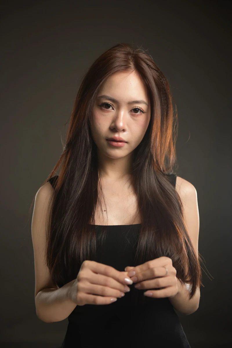 Studio portrait with long dark hair against a dark background