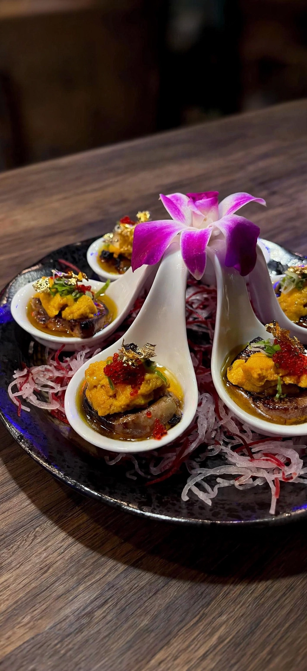 Seafood bites in porcelain spoons with orchid garnish