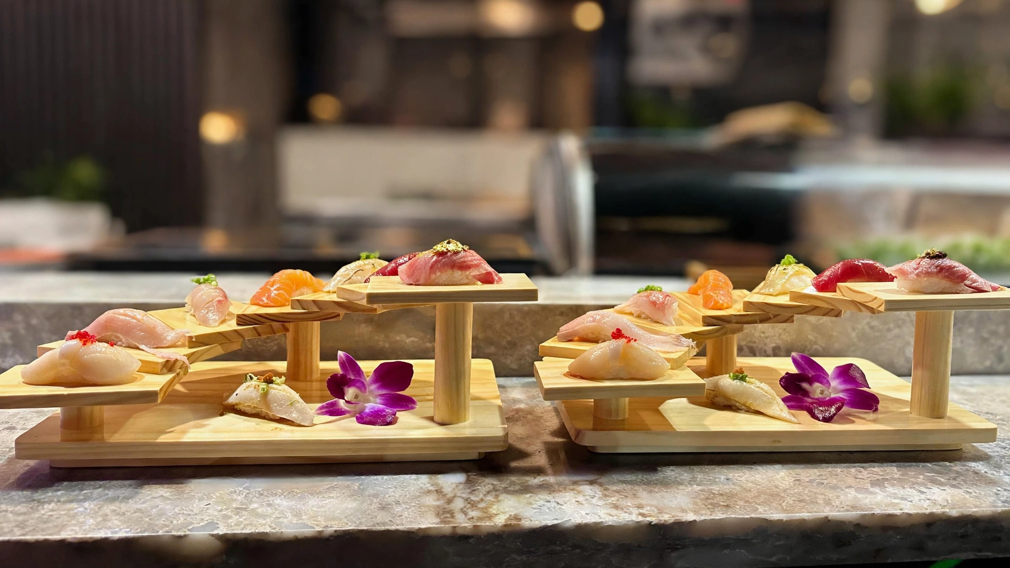 Nigiri presented on two wooden displays at the sushi counter