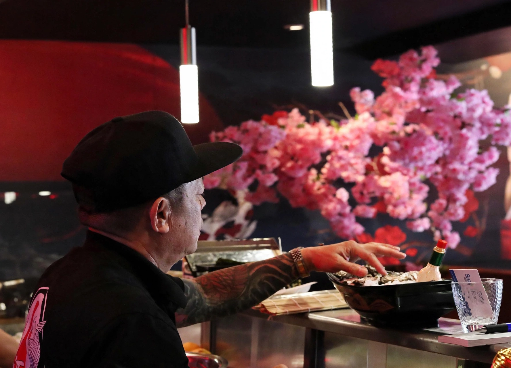 Chef preparing food at the sushi counter with floral decor behind him