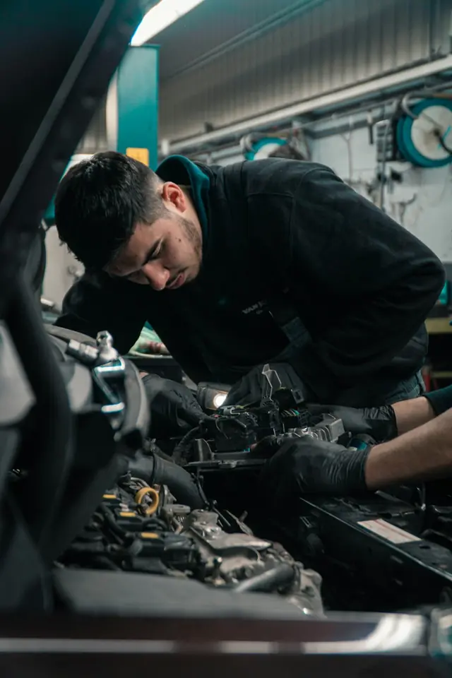 Auto repair · Mechanic working over an open engine bay — illustrative stock photograph